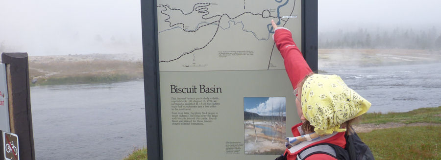 Anita zeigt auf Trailhead Bisquit Basin